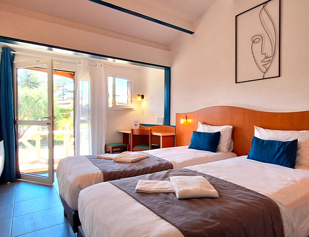 Chambre lumineuse du Relais du Moulin Neuf à Barbaste avec deux lits simples, terrasse privative et vue sur le parc.