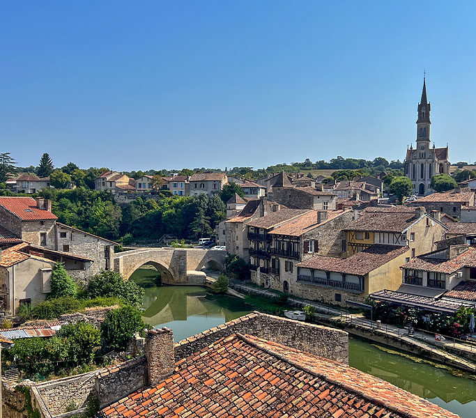 Vue panoramique sur la ville de Nérac, ses toits en pierre, le pont de la Baïse et l’église Saint-Nicolas.